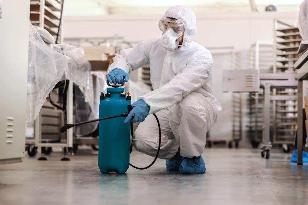 worker-protective-uniform-with-mask-rubber-gloves-crouching-spraying-with-disinfectant-food-factory-corona-outbreak-concept-min